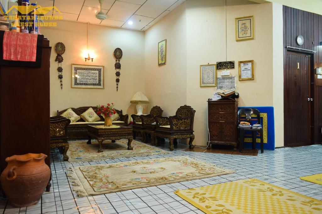 Teratak Ibunda Guest house في كوتا بْهارو: غرفة معيشة مع أريكة وكراسي في غرفة