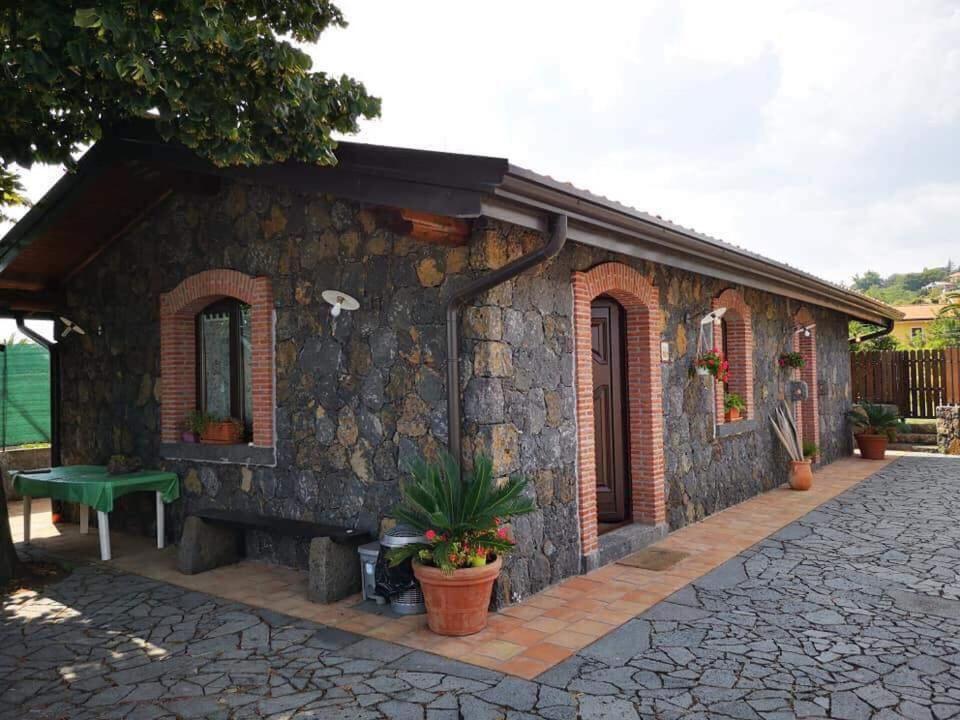 una casa de piedra con un banco verde delante de ella en Il Tiglio en Viagrande