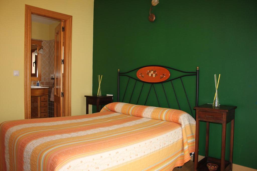 1 dormitorio con cama y pared verde en El Rincon del Labrador en La Santa Espina