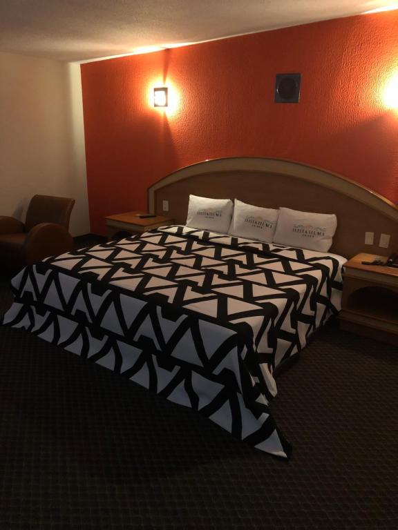 - une chambre avec un lit et une couette noire et blanche dans l'établissement Hotel Puerta del Sol, à Toluca