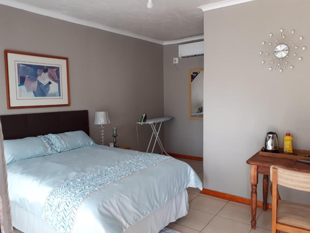 a bedroom with a bed and a table in it at Dreamwood Guest House in Nelspruit
