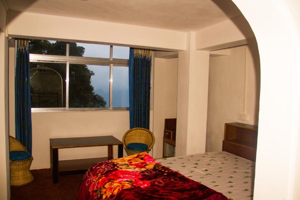 1 dormitorio con cama, ventana y mesa en Riva homestay family room en Darjeeling