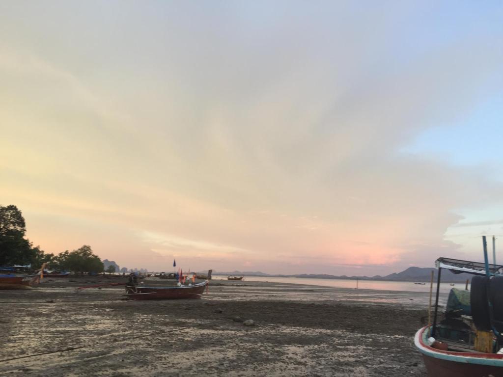 um grupo de barcos sentados na praia ao pôr do sol em Koh Mook Rem Ley em Trang