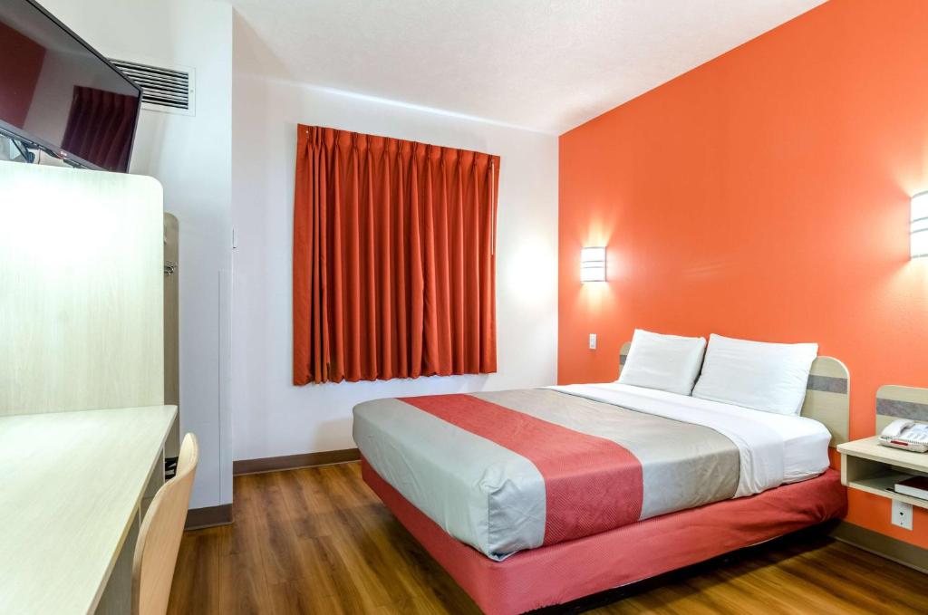 Habitación de hotel con cama con pared de color naranja en Motel 6-Kearney, NE, en Kearney