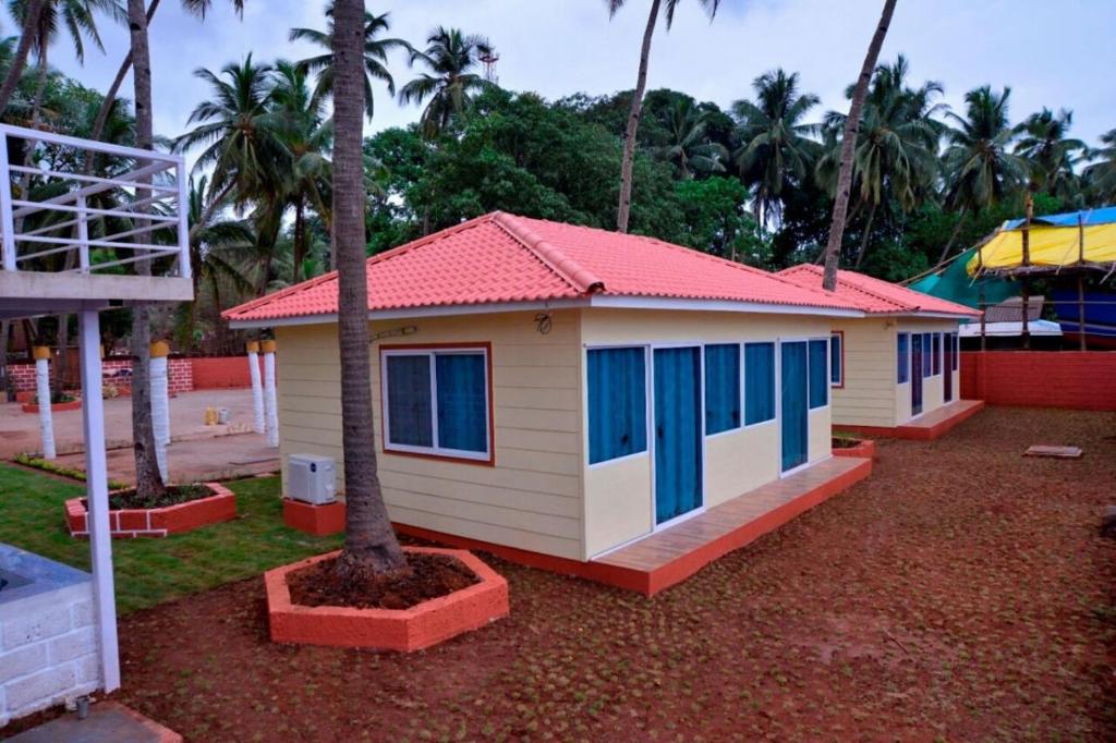 una pequeña casa con ventanas azules y una palmera en Sushegad Holiday Homes, en Ratnagiri