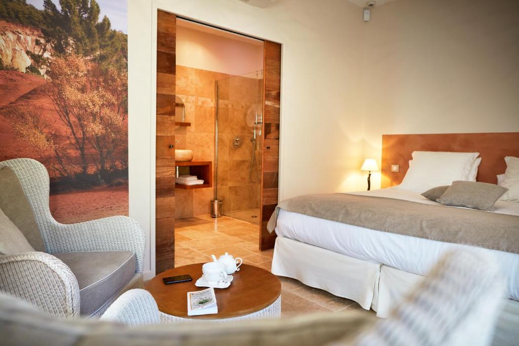 a hotel room with a bed and a table and chairs at Les Mazets du Luberon in Puget