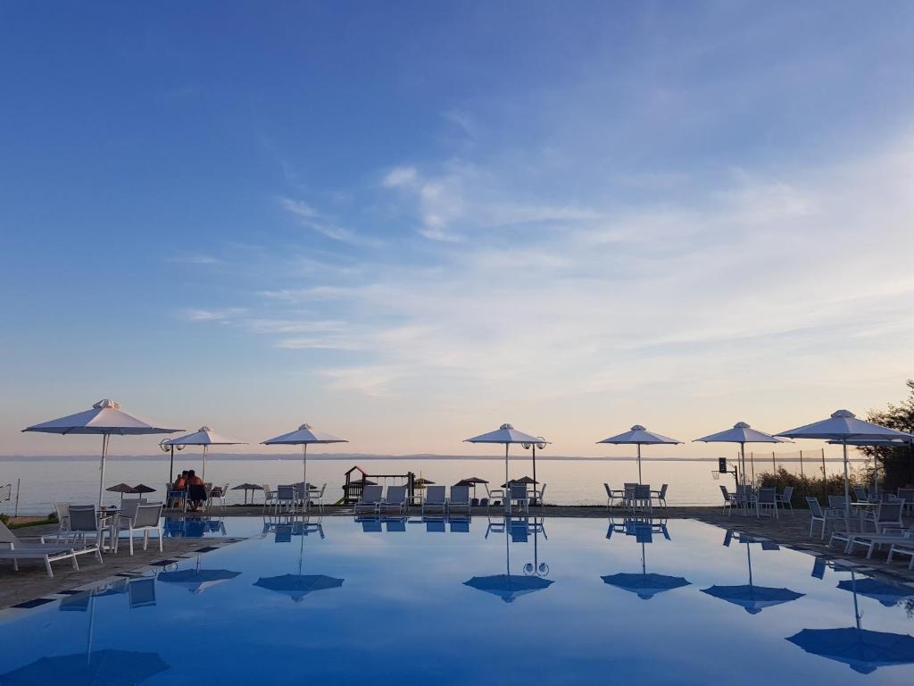una piscina con mesas y sombrillas en Alkinoos Beach Hotel en Gerakini
