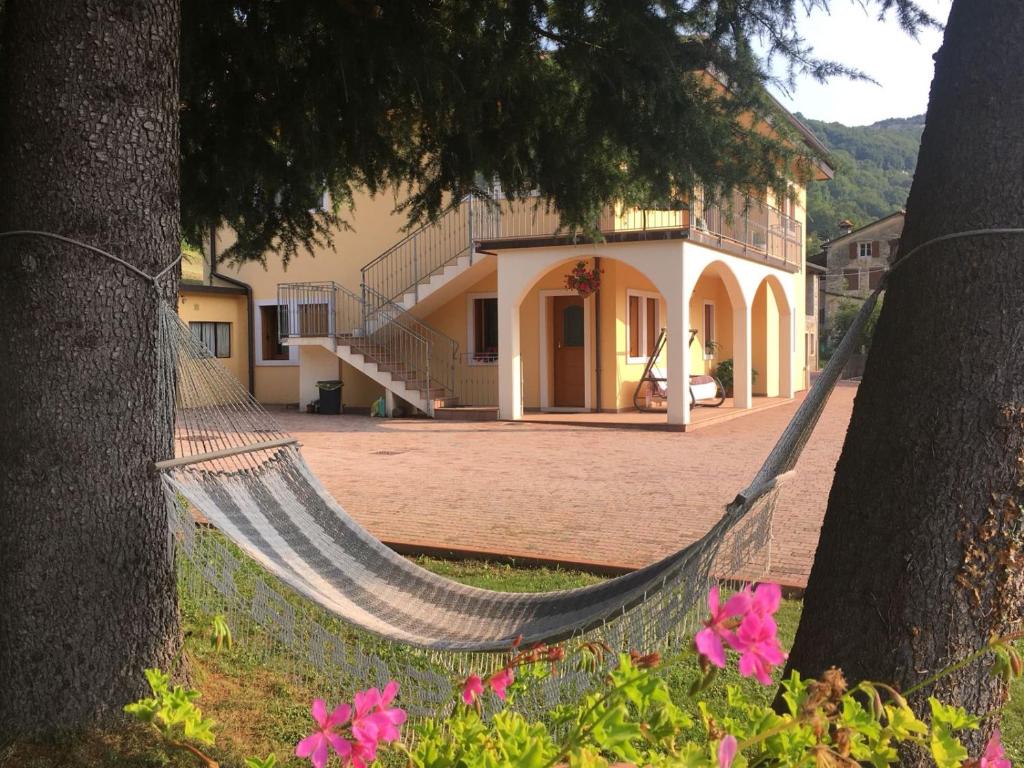 a hammock between two trees in front of a house at Appartamento da Cristina in Conco