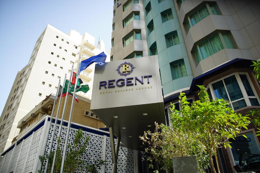 um sinal para um resort em frente a um edifício em Regent Hotel Apartments em Kuwait