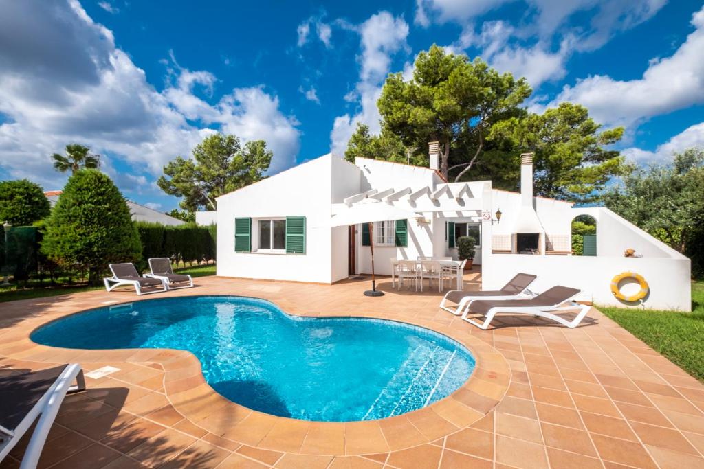 a villa with a swimming pool in front of a house at Villas Geisan in Ciutadella