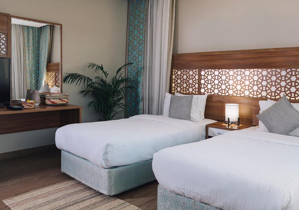 a hotel room with two beds and a table at فندق جمانة ينبع in Yanbu