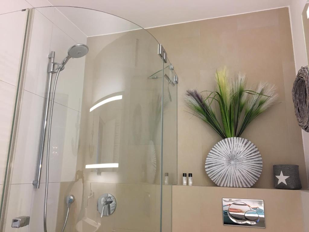 シャルボイツにあるStrandSUITE Scharbeutz Meerblickのバスルーム(ガラスドア付きのシャワー付)