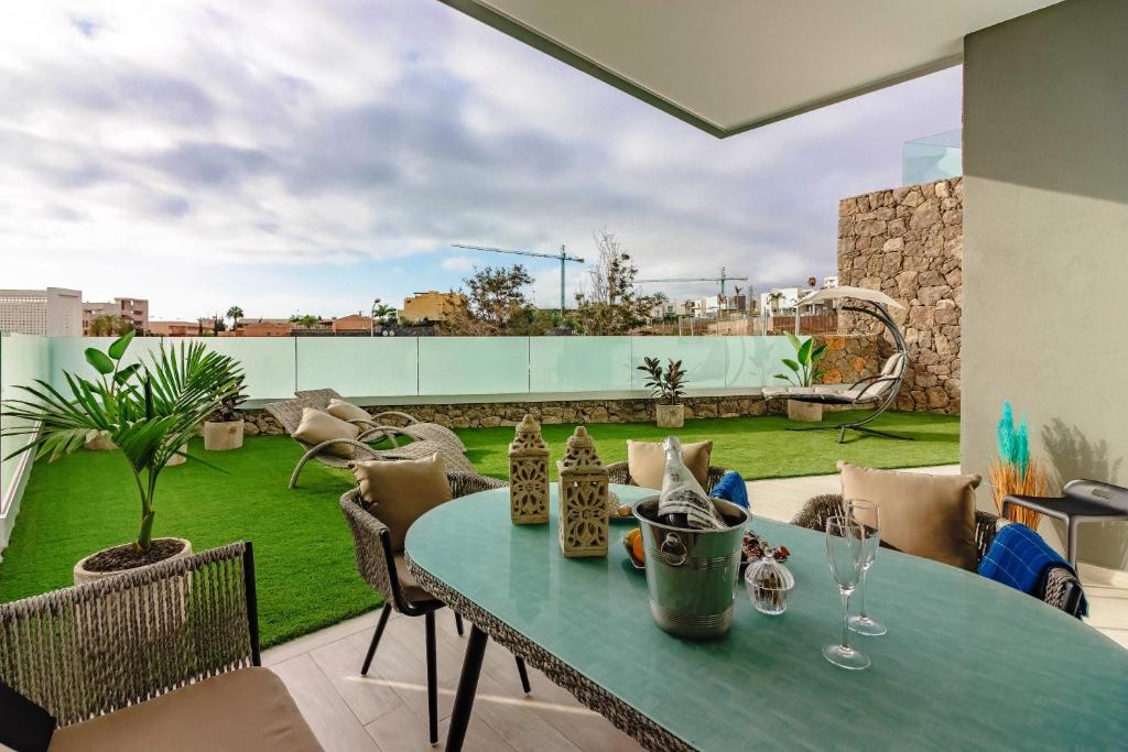 un patio con mesa y sillas y un jardín en Deluxe 2 bedrooms with chillout terrace, en Playa Paraiso