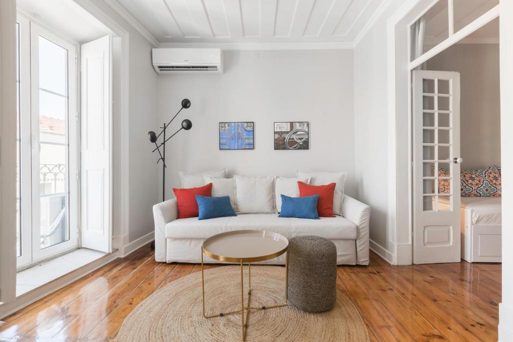 a living room with a white couch with colorful pillows at Charming Apartment Rua da Rosa 33 in Lisbon