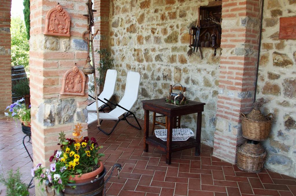 a patio with a table and white chairs and a brick wall at Tenuta La Silva in Seggiano