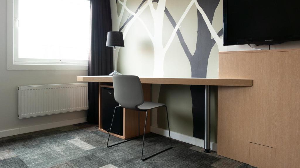 - un bureau dans une chambre avec une chaise et une télévision dans l'établissement City Living Sentrum Hotel, à Trondheim