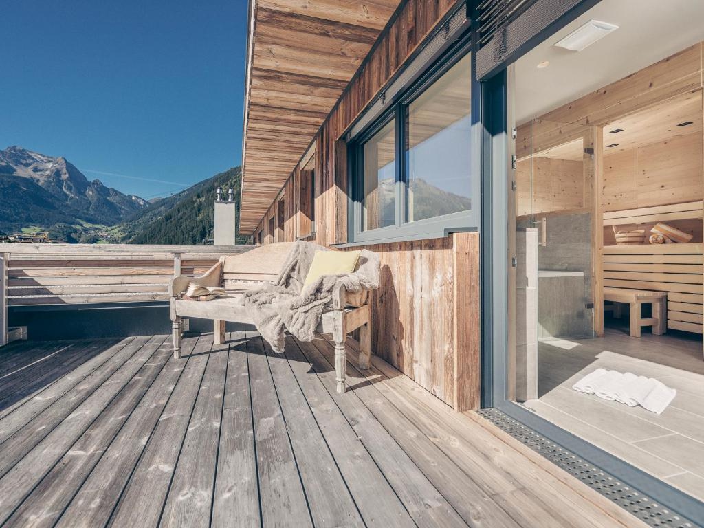 a wooden deck with a bench on the side of a house at Postresidenz in Mayrhofen