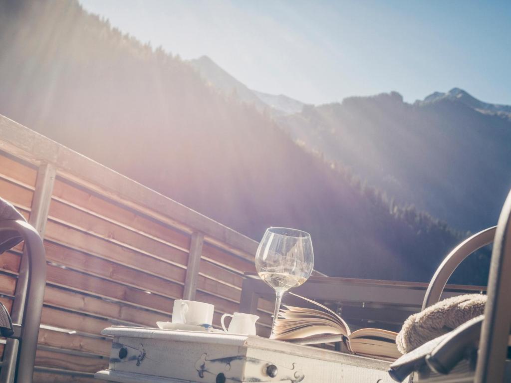 a glass of wine sitting on a table with a book at Postresidenz in Mayrhofen