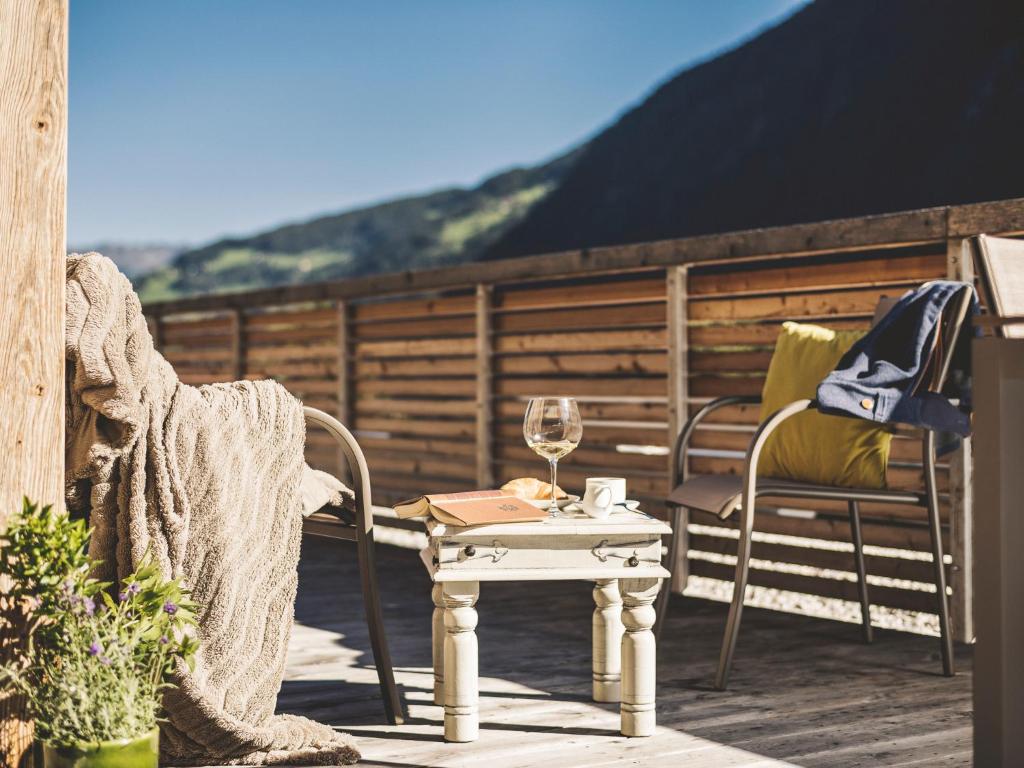 a table and chairs on a porch with a glass of wine at Postresidenz in Mayrhofen