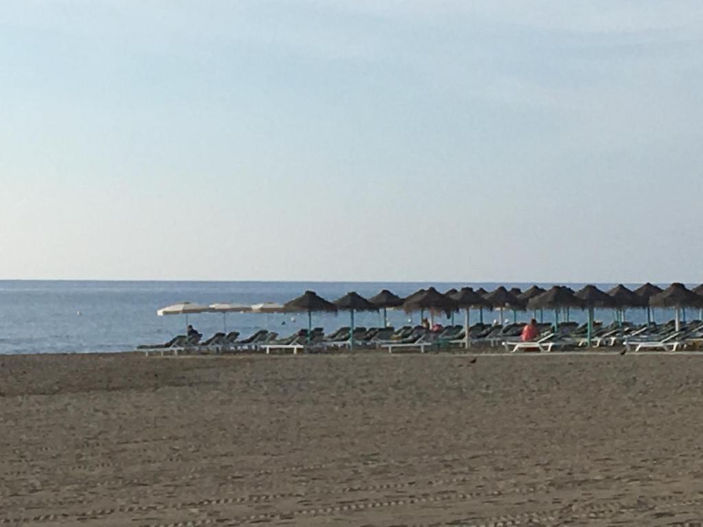 una playa con sillas y sombrillas y el océano en Apartamentos SOL y PLAYA Torremolinos, en Torremolinos