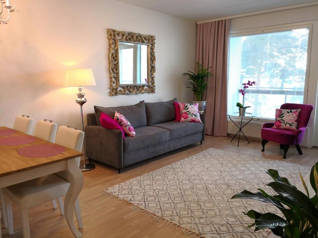 a living room with a couch and a table at Charming Pine View Apartment in Vantaa