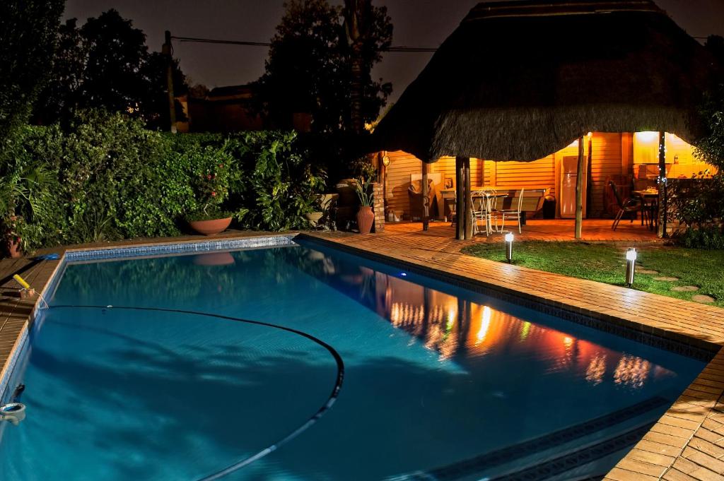 a swimming pool in a backyard at night at Rest-a-While Guest House - Pretoria in Pretoria
