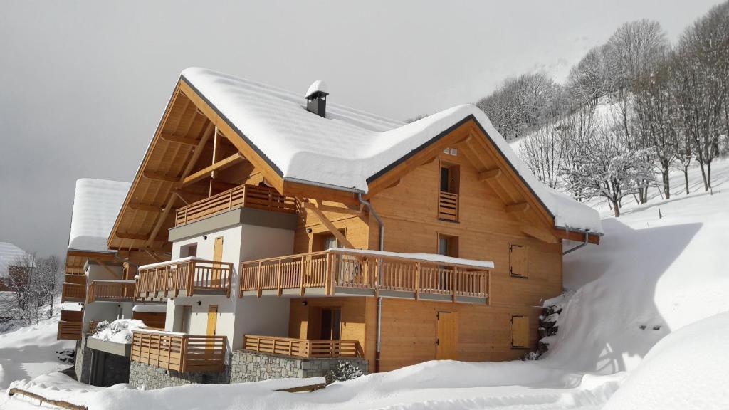 una cabaña de madera en la nieve con nieve en 63 Route du Rochas, en Vaujany