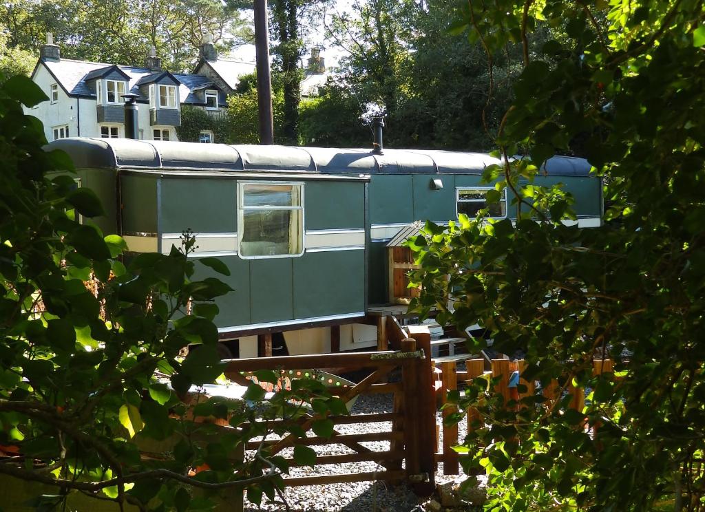 a green train is parked on the tracks at Showman's Wagon at Coed Cae in Dolgellau