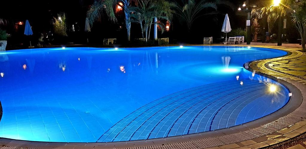 Deluxe Apartment Delta Sharm في شرم الشيخ: حمام سباحة أزرق كبير في الليل