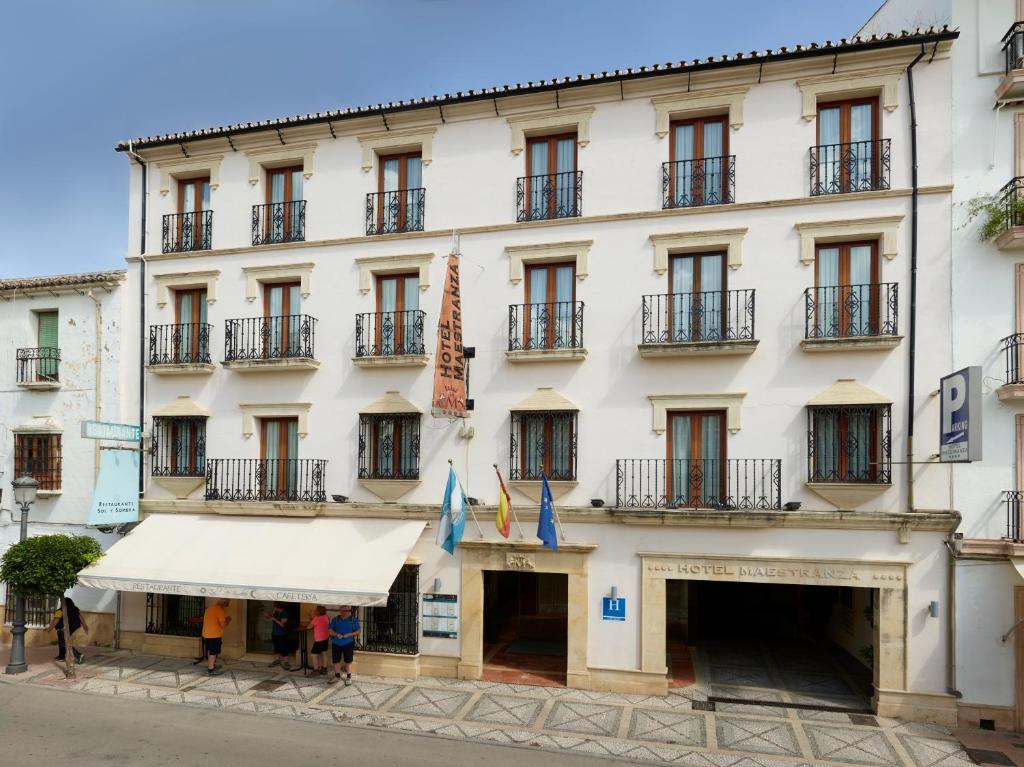 ein großes weißes Gebäude mit Leuten, die davor laufen in der Unterkunft Hotel Maestranza in Ronda