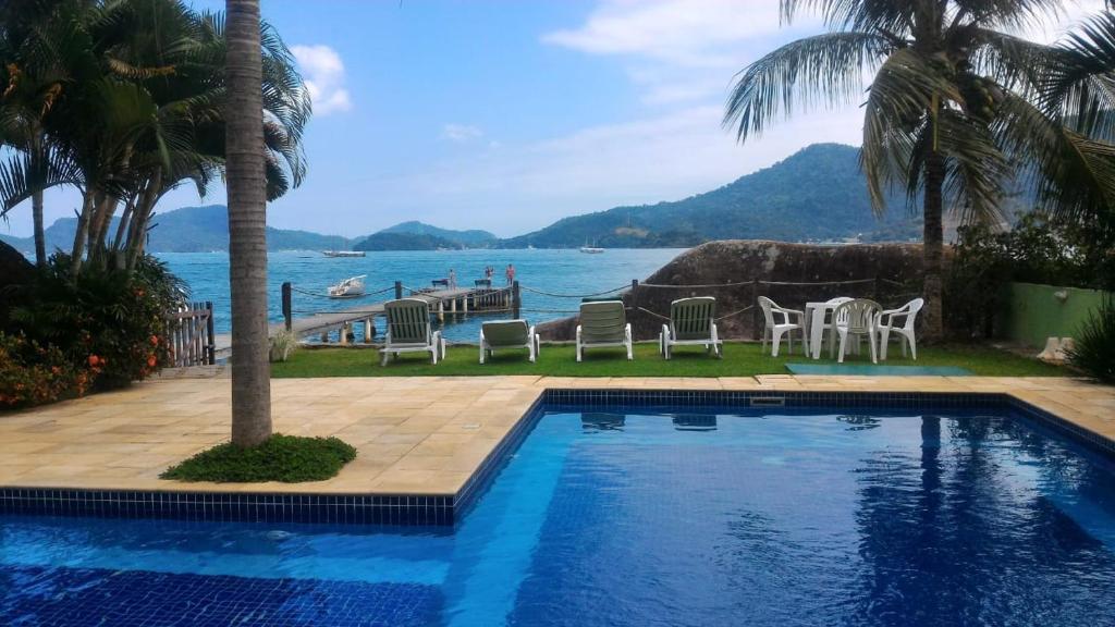 una piscina con sillas y vistas al océano en Apartamento em Condominio Fechado - Angra dos Reis - Piscina, Praia, Lazer, en Angra dos Reis