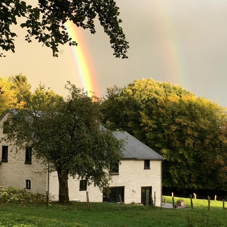 a rainbow in the sky over a white house at La Chambre de la Gotale in Manhay