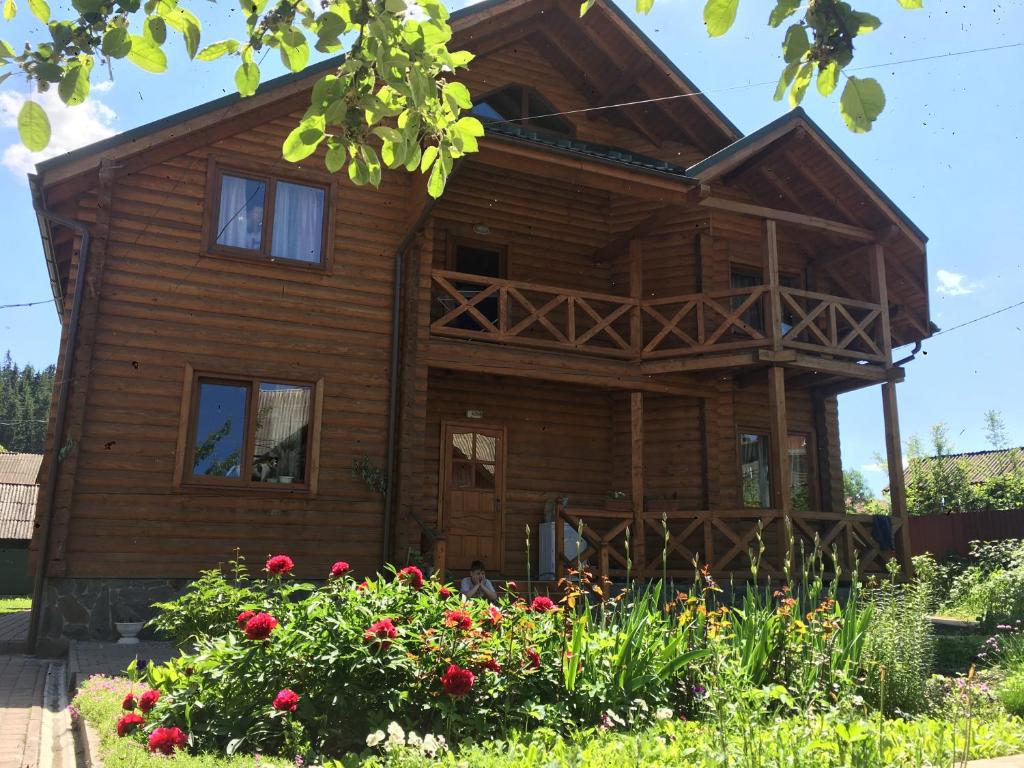 une maison en bois avec des fleurs devant elle dans l'établissement Барви Карпат, à Vorokhta