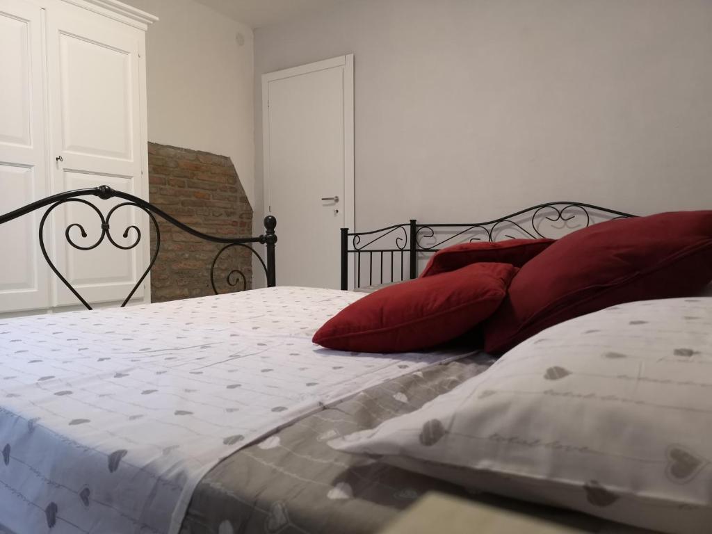 sypialnia z łóżkiem z czerwonymi poduszkami w obiekcie Appartamento Le Cicale w mieście Ferrara