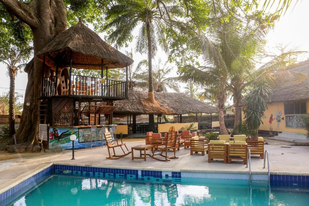 ein Resort mit einem Pool mit Stühlen und einem Baum in der Unterkunft Fromager in Cap Skirring