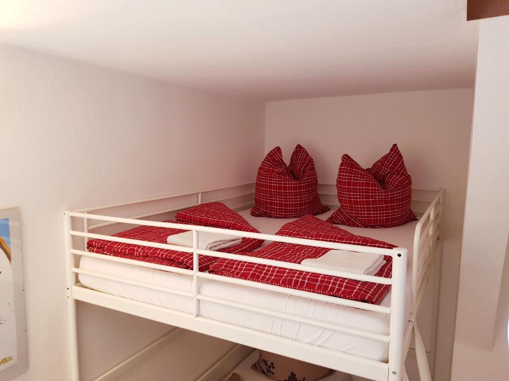 Litera blanca con almohadas rojas en Casa Conne en Rudolstadt