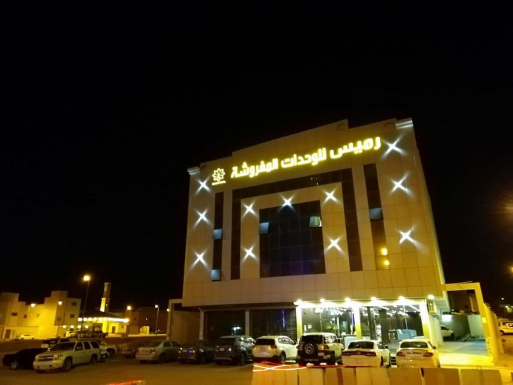 un edificio con auto parcheggiate in un parcheggio di notte di Ramis Furnished Units a Buraydah