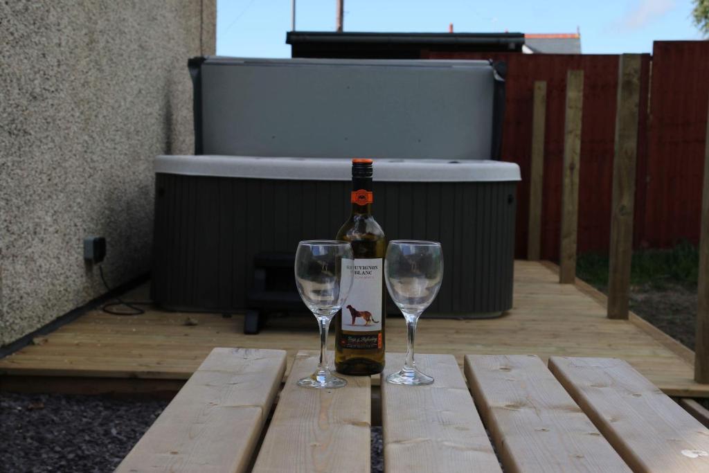 Una botella de vino y dos copas en una mesa de madera. en Swyn y Mor beach close Pet friendly hot tub, en Barmouth