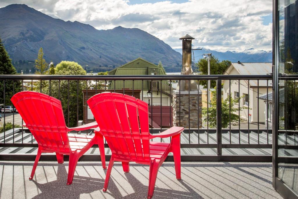 two red chairs sitting on a balcony with a view at Apartment 33 - Post Office Lane in Wanaka