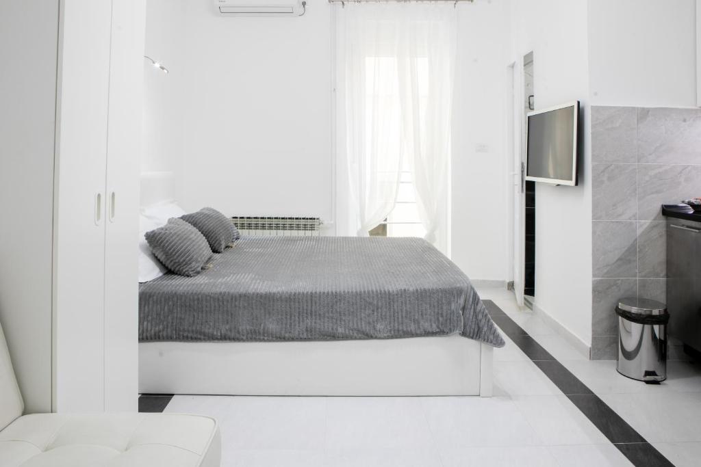 ein weißes Schlafzimmer mit einem Bett und einem TV in der Unterkunft Natalie's Studio in Belgrad