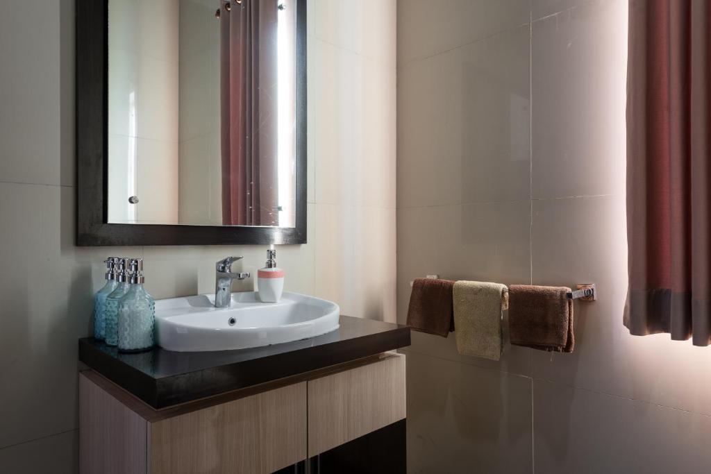 a bathroom with a sink and a mirror and towels at Villa Melasti Wardana in Uluwatu