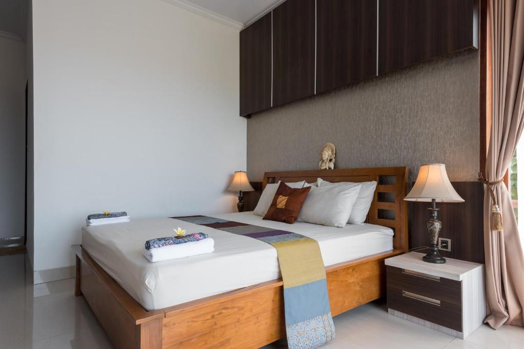 a bedroom with a large bed with a wooden headboard at Villa Melasti Wardana in Uluwatu