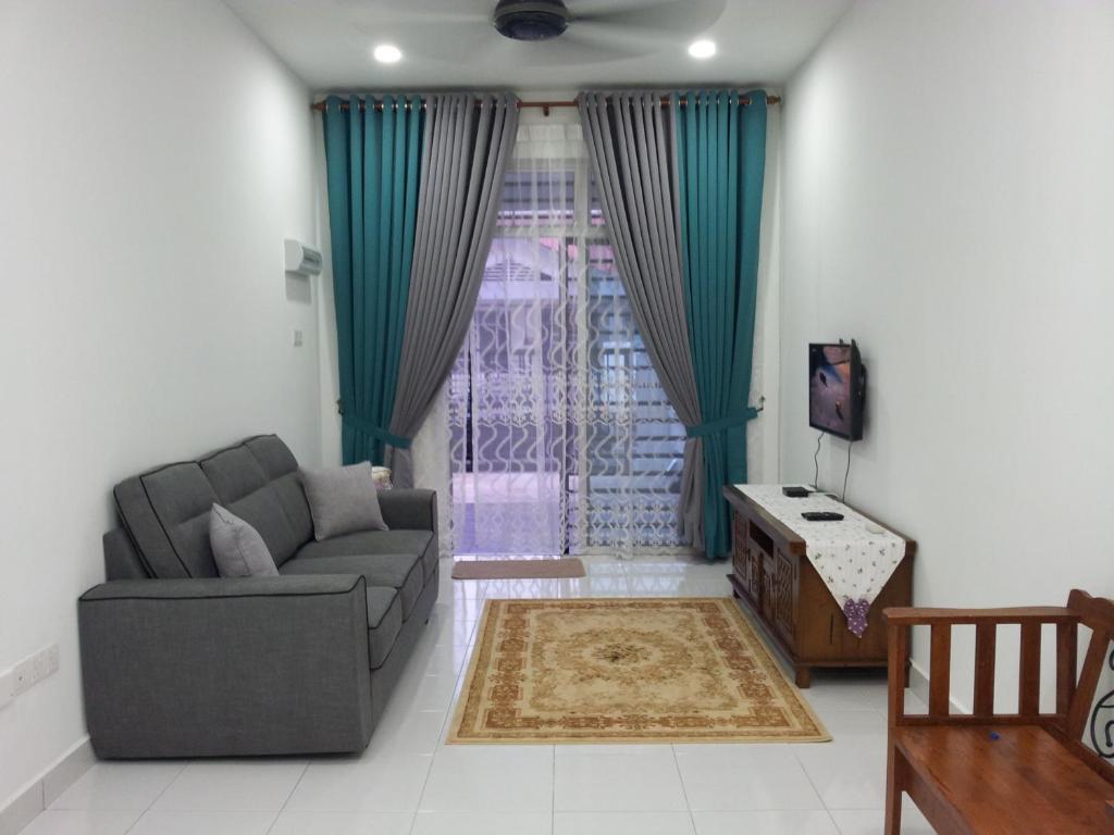 Ahnaf Homestay Bandar Penawar Desaru في دِسارو: غرفة معيشة بها أريكة وطاولة وتلفزيون