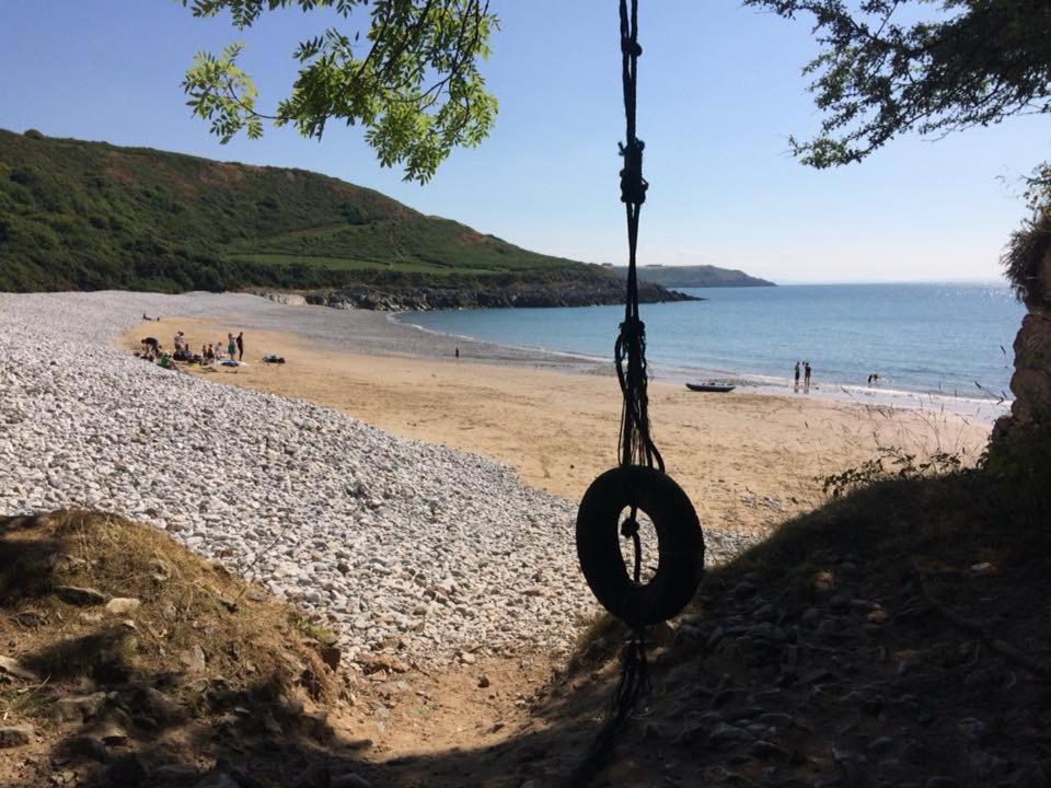 a tire swing hanging from a tree on a beach at Ortari@70 in Swansea
