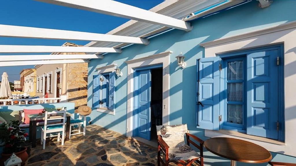 a patio with a table and chairs and a blue wall at Amazing House in Halki in Halki