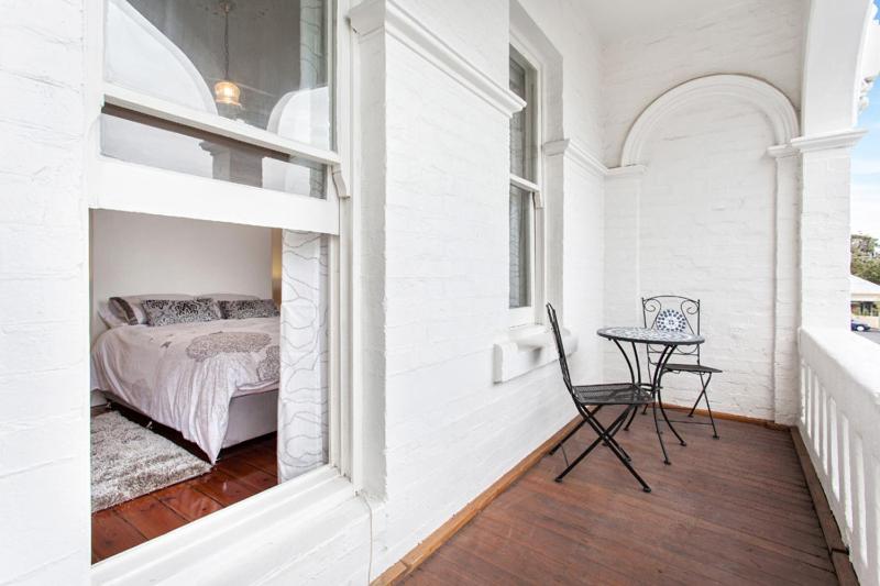 Un dormitorio con una cama y una mesa en el balcón. en The Crofts, en Melbourne