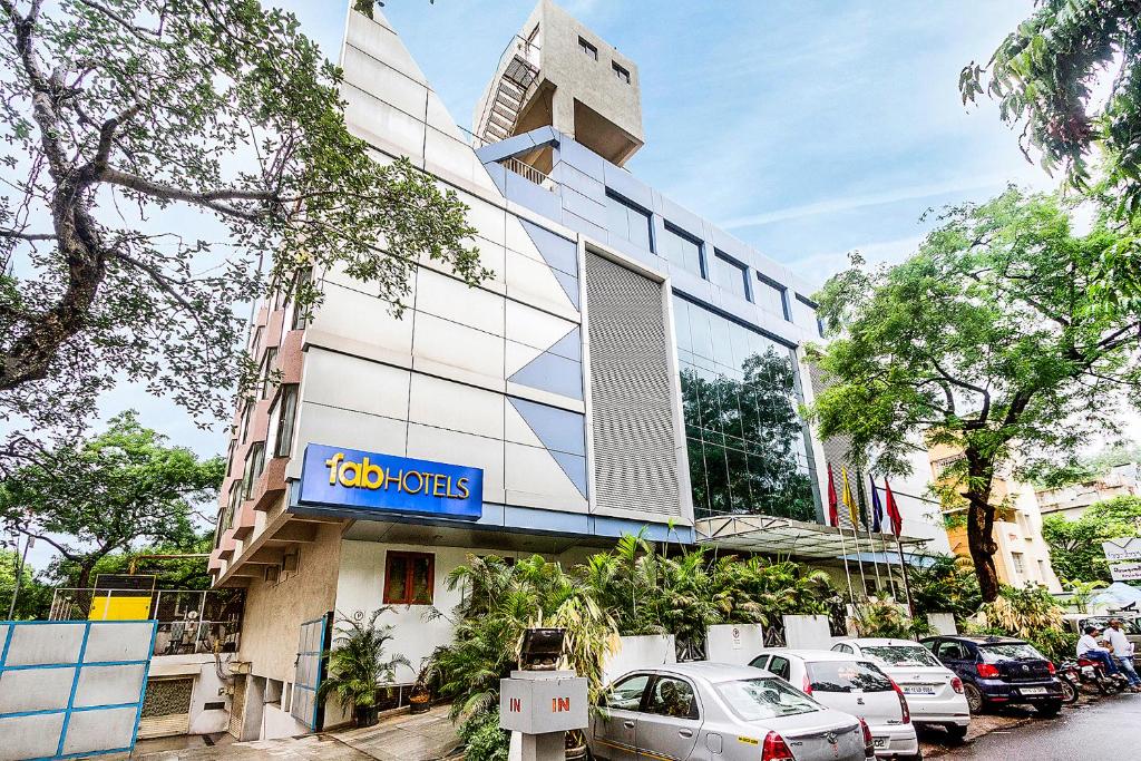 un edificio con coches estacionados frente a él en Hotel Gandharva Shivajinagar en Pune