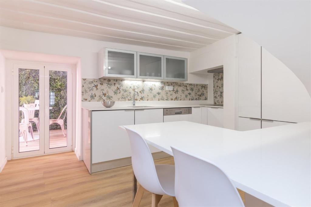 a kitchen with white cabinets and a white table at Travessa fiéis de deus in Lisbon