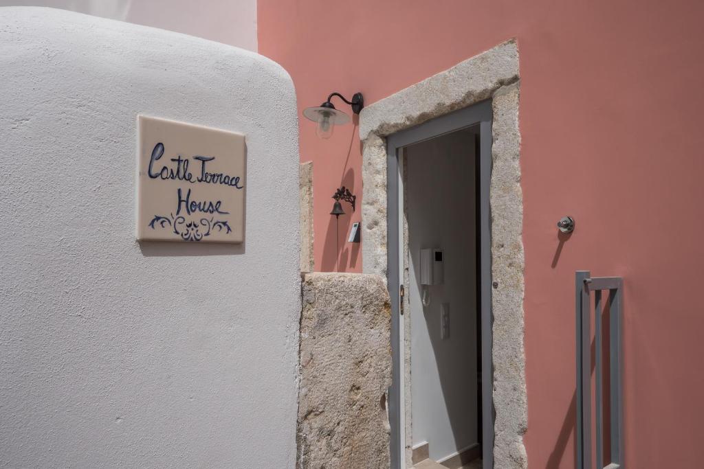 uma porta para um edifício cor-de-rosa com um sinal que diz "Vila Terra tem piedade" em Castle Terrace Exclusive Apartment - Home By The Castle Apartment em Lisboa