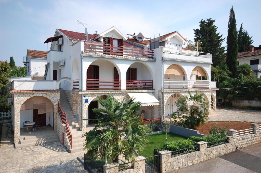 une grande maison blanche avec un palmier en face de celle-ci dans l'établissement Apartment Ivan, à Malinska